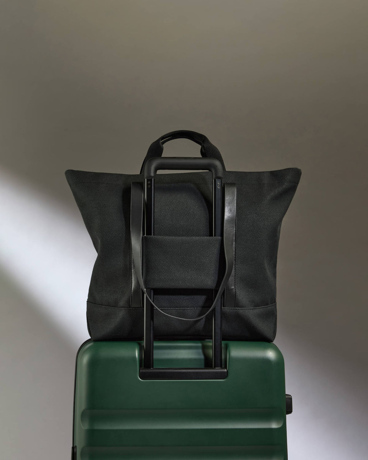 a black bag on top of a green suitcase