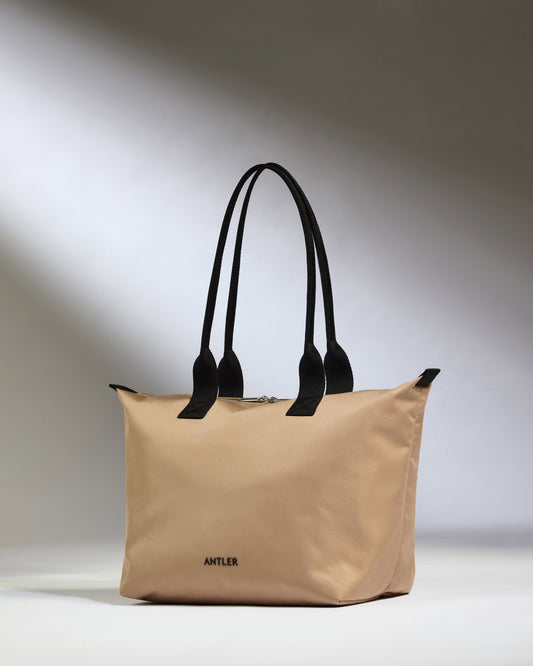 a beige bag with black handles