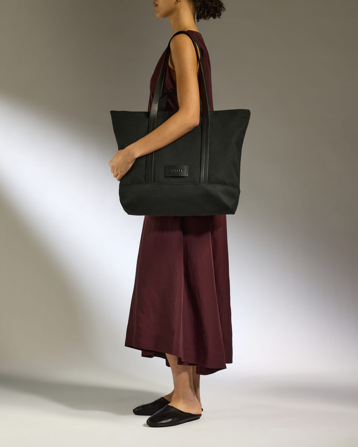 a woman in a dress holding a large black bag
