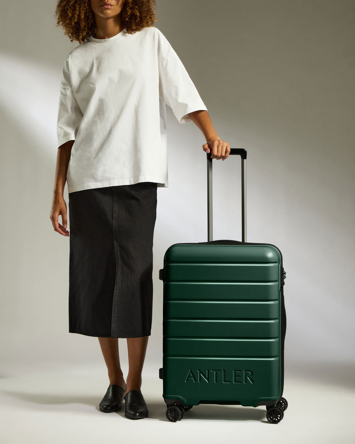 a woman in a white shirt and black skirt with a green suitcase