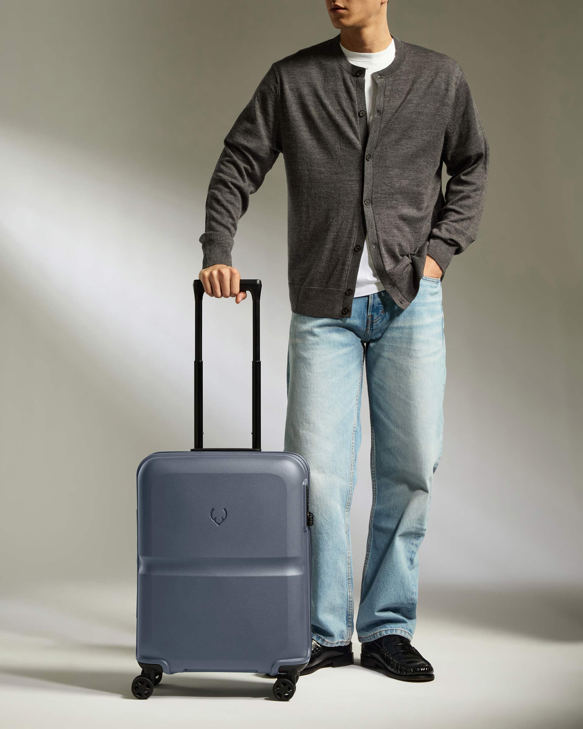 a man standing with his hand in his pocket and a suitcase