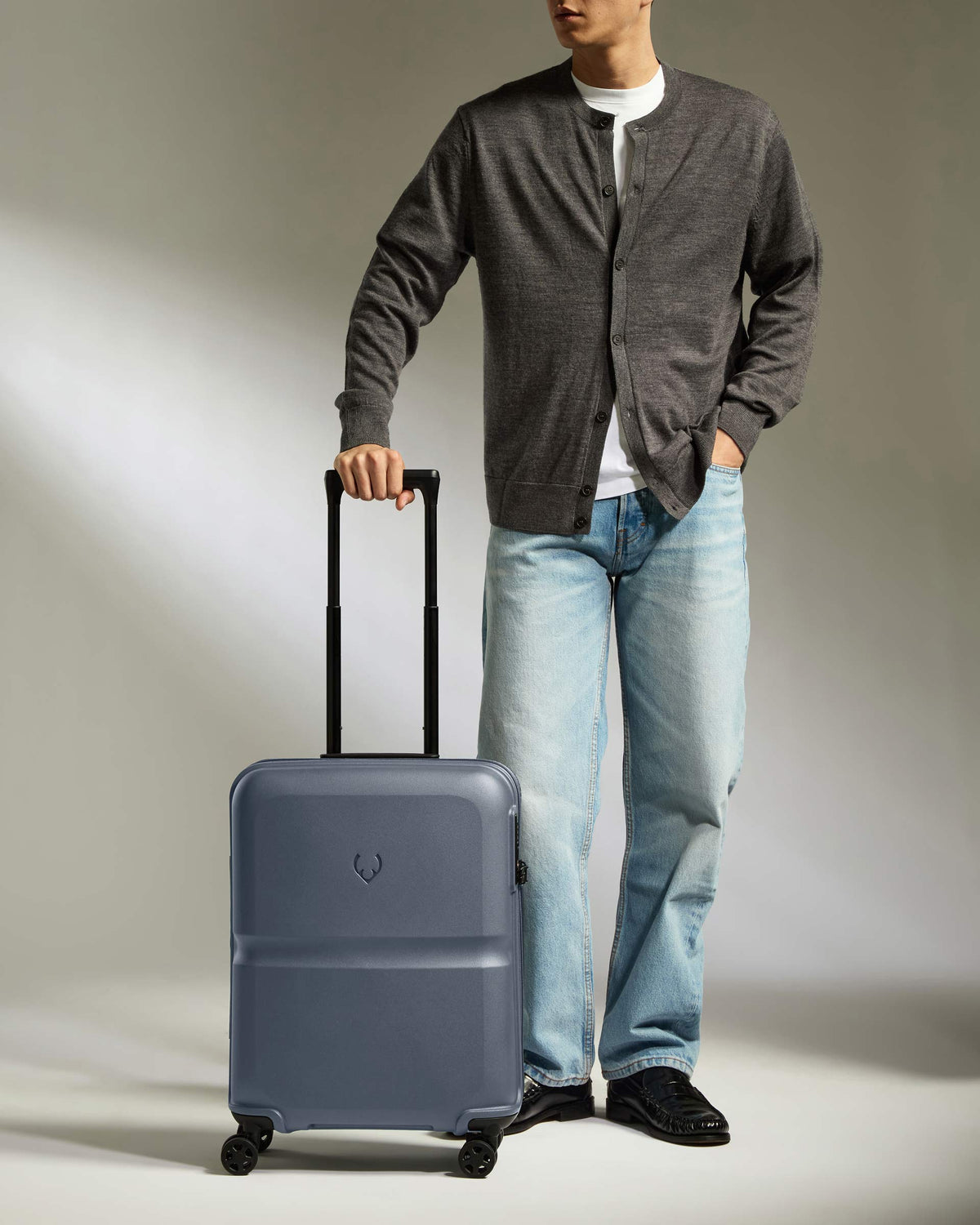 a man standing with his hand in his pocket and a suitcase