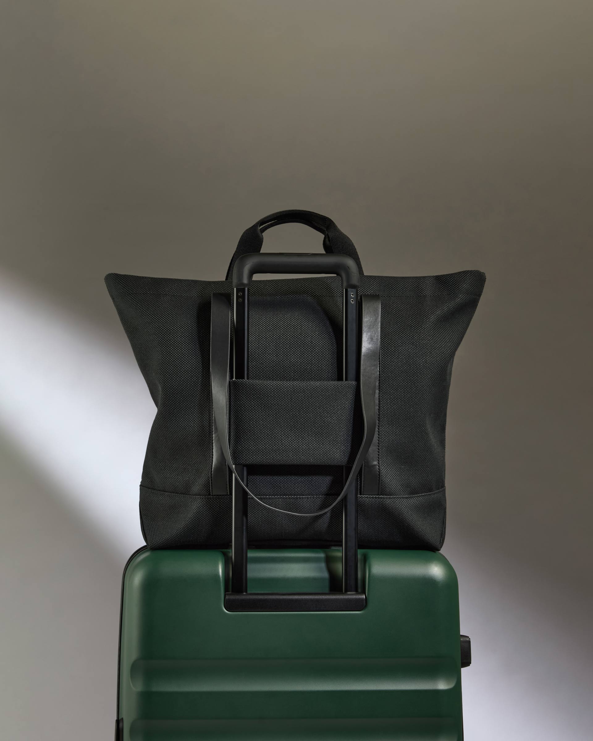 a black bag on top of a green suitcase