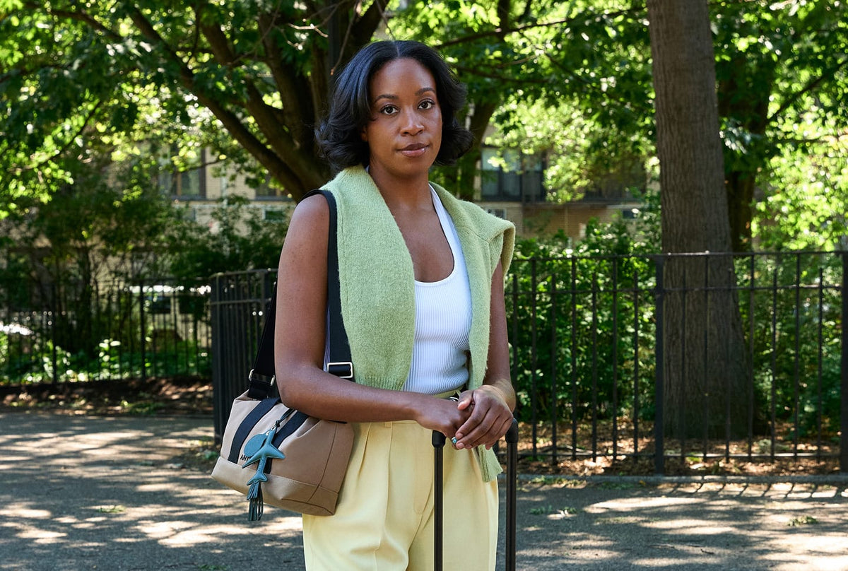 a woman standing outside with a bag and a cane