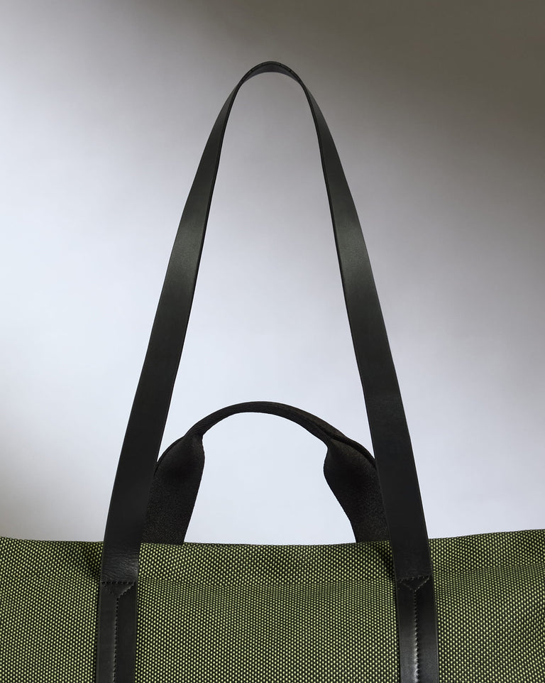 a green bag with black straps with Gateway Arch in the background
