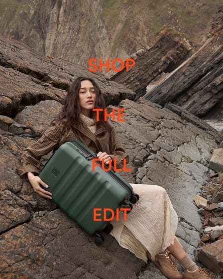 a woman sitting on a rock with a suitcase