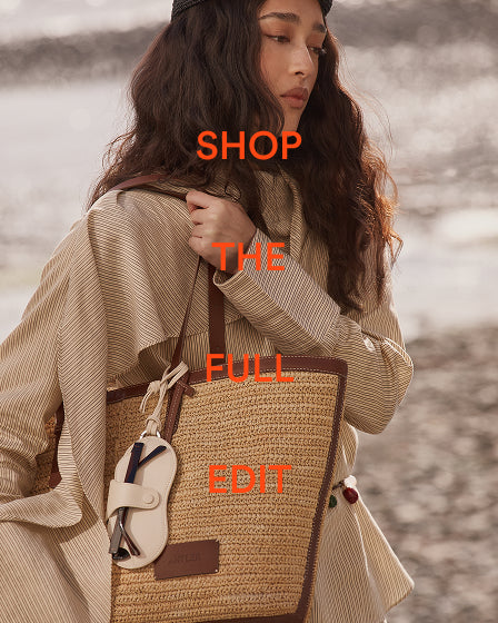 a woman with long brown hair and a tan bag